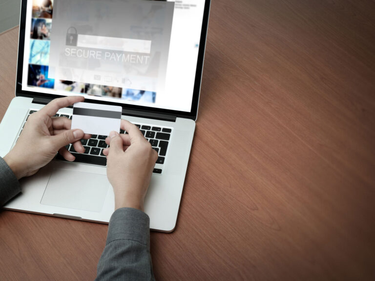 Man holding a credit card while sitting at a laptop