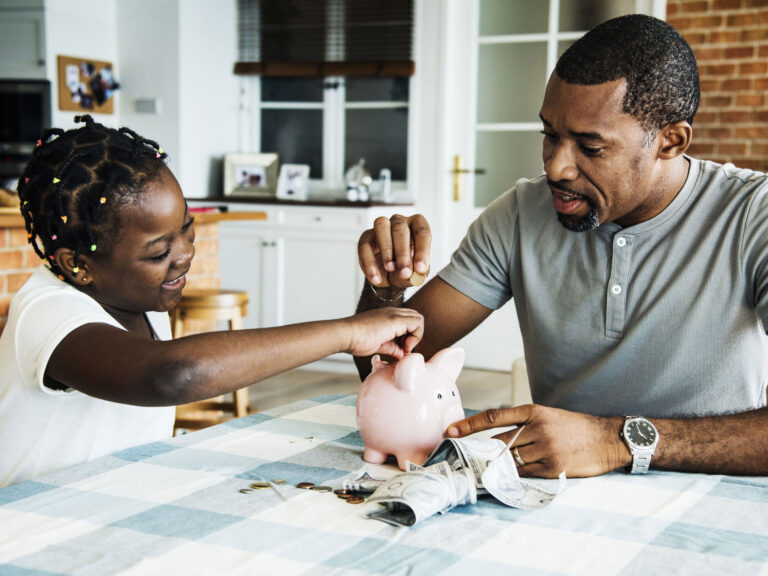 Father and daughter putting money in a piggy bank