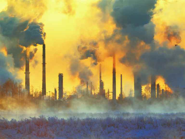 Smokestacks and carbon emissions against yellow sky