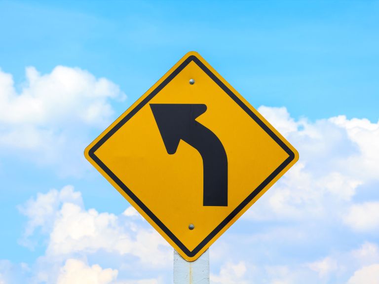 Curve ahead sign with cloudy sky in background