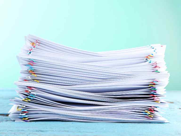 Stack of papers with paperclips against blue background