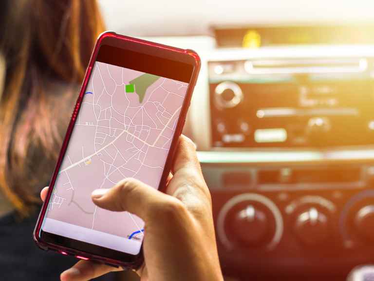 Hand holding phone showing a map while someone else drives