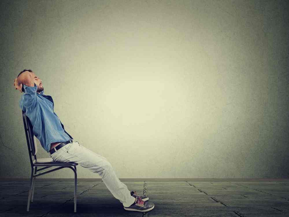 Man in a blue shirt relaxing in a chair after practicing time management skills